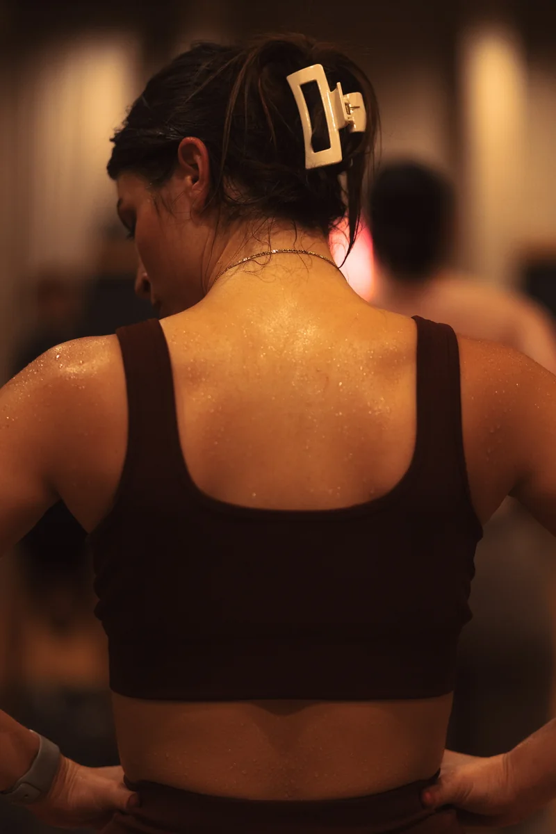 Sweat across a practitioner’s shoulders and back during class.